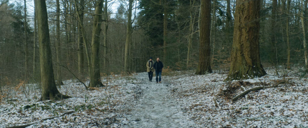 Kenny (Nathaniel Parker) and Andy (Joel Beckett) walking through the woods together.