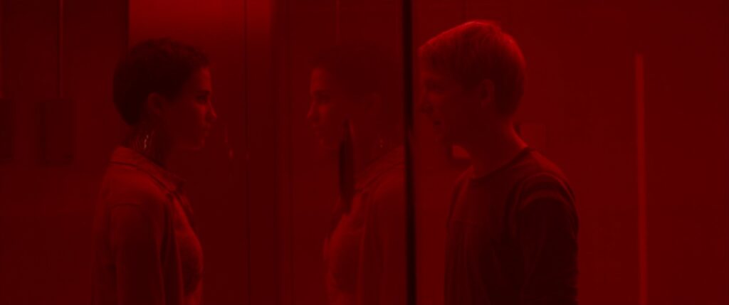 Alicia Vikander and Domhnall Gleeson bathed in red