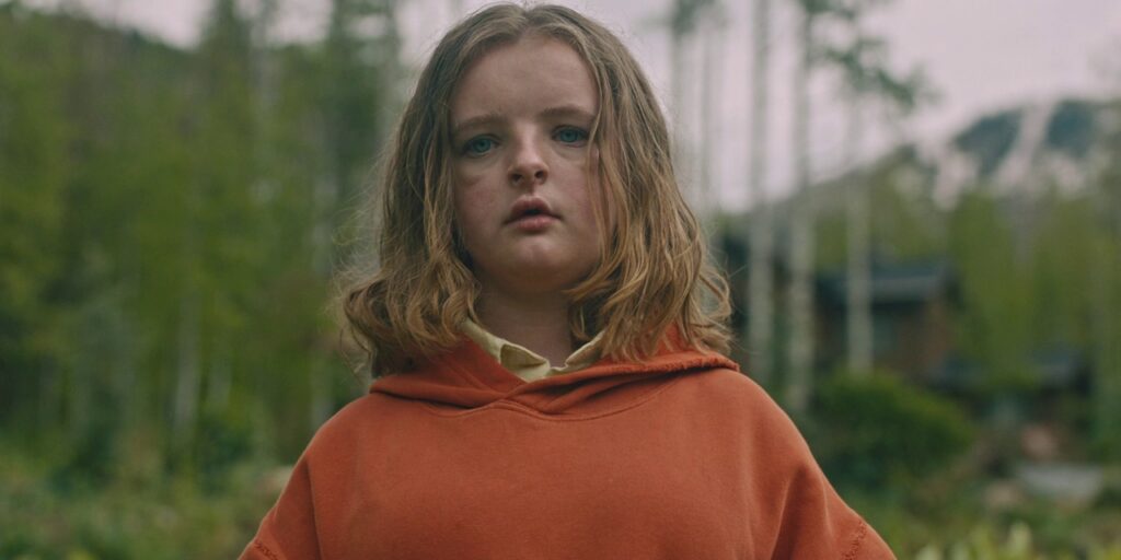 Actor Milly Shapiro wearing a red hoodie with forest backdrop